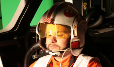 Dirk in Flieger-Kombi und Helm im Cockpit vor Greenscreen.